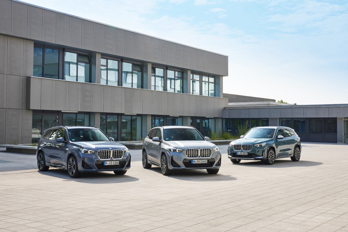 Drei Elektroautos BMW iX1 stehen vor einem Bürogebäude 