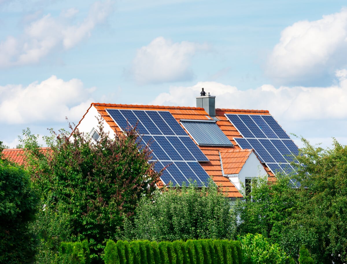 Ein Haus im Grünen mit mehreren Solarmodulen auf dem Dach.